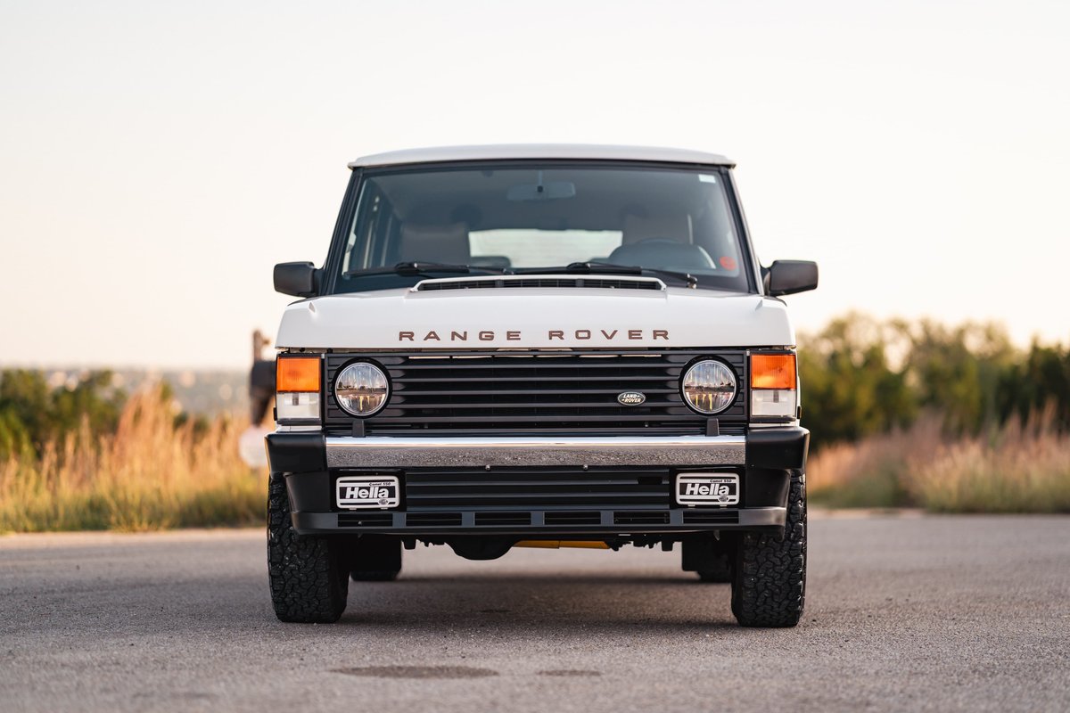 Front view of a white 1995 Range Rover County with black trim and Hella fog lights.