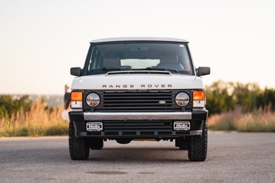 Front view of a white 1995 Range Rover County with black trim and Hella fog lights.
