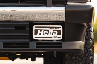Front bumper of a white 1995 Land Rover Range Rover County with Hella Comet 550 fog lights.