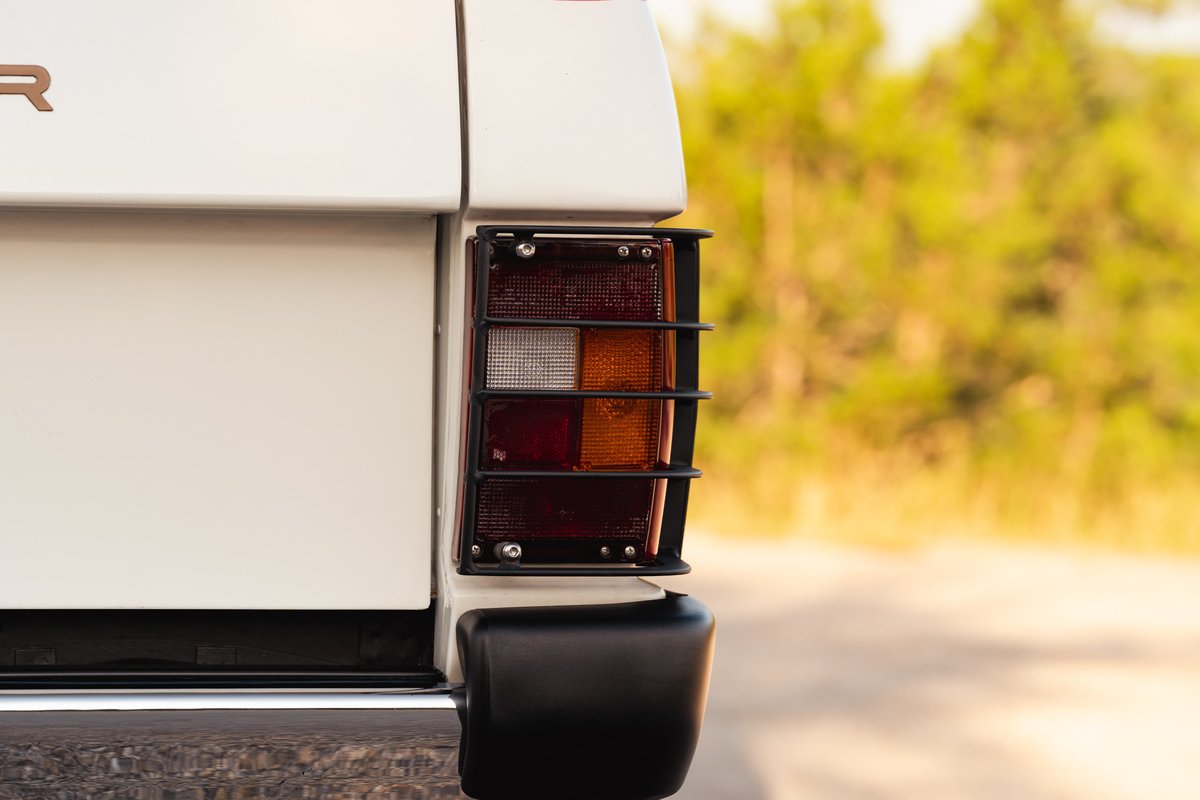 Close-up rear shot of a white 1995 Land Rover Range Rover County's taillight with protective grille.