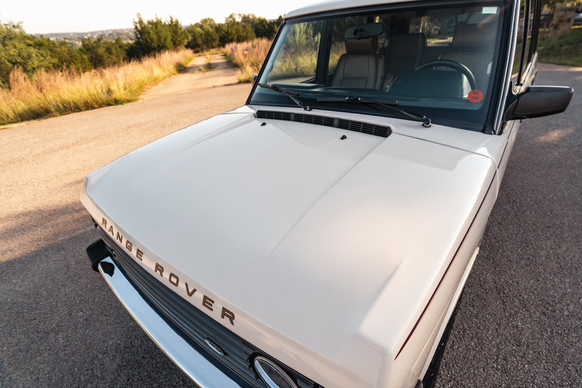 White 1995 Range Rover County on a dirt road. Front hood and grille visible.
