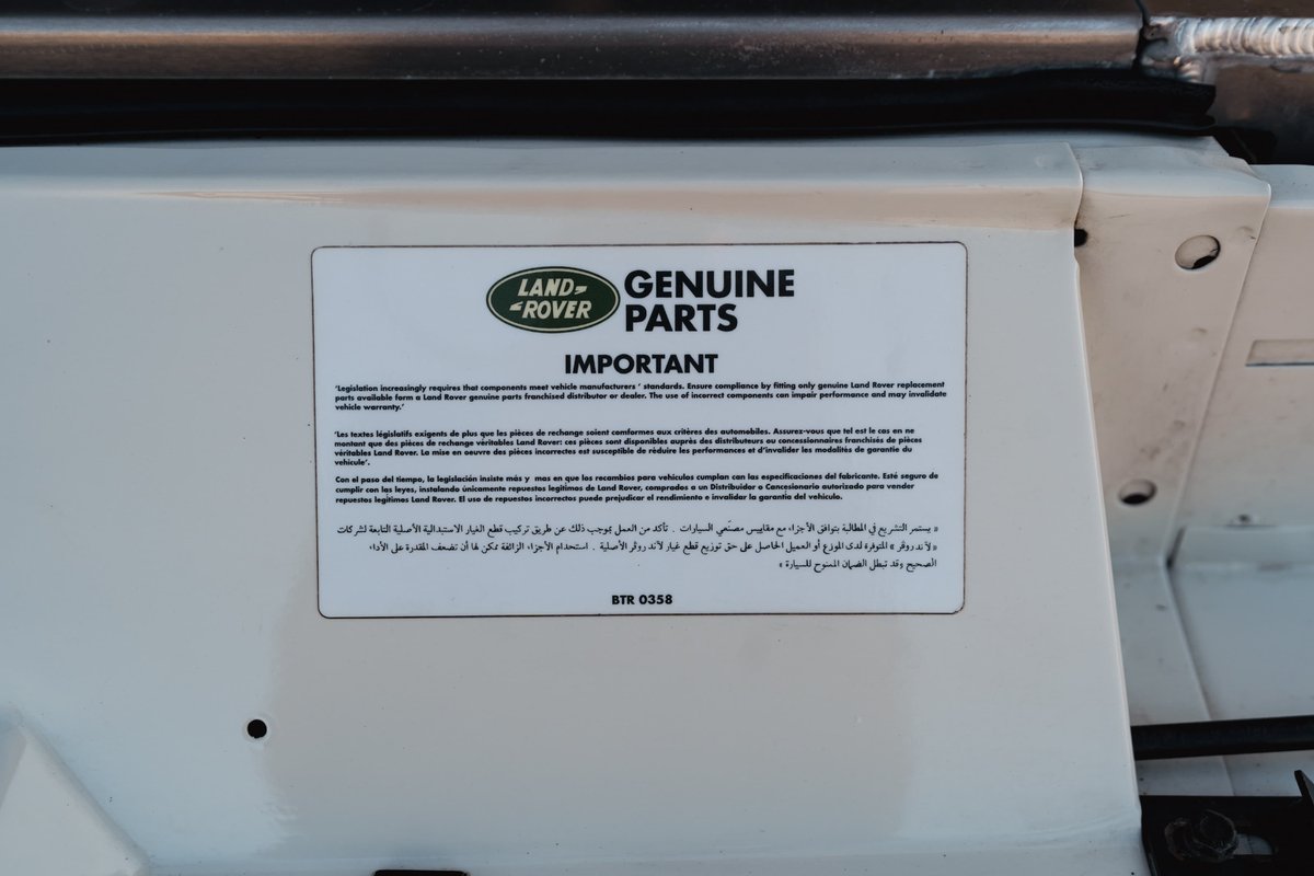 Close-up of a sticker on a white 1995 Land Rover Range Rover County with "Genuine Parts" text.