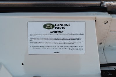 Close-up of a sticker on a white 1995 Land Rover Range Rover County with "Genuine Parts" text.