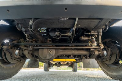 Underside of a white 1995 Land Rover Range Rover County showing suspension and drivetrain.