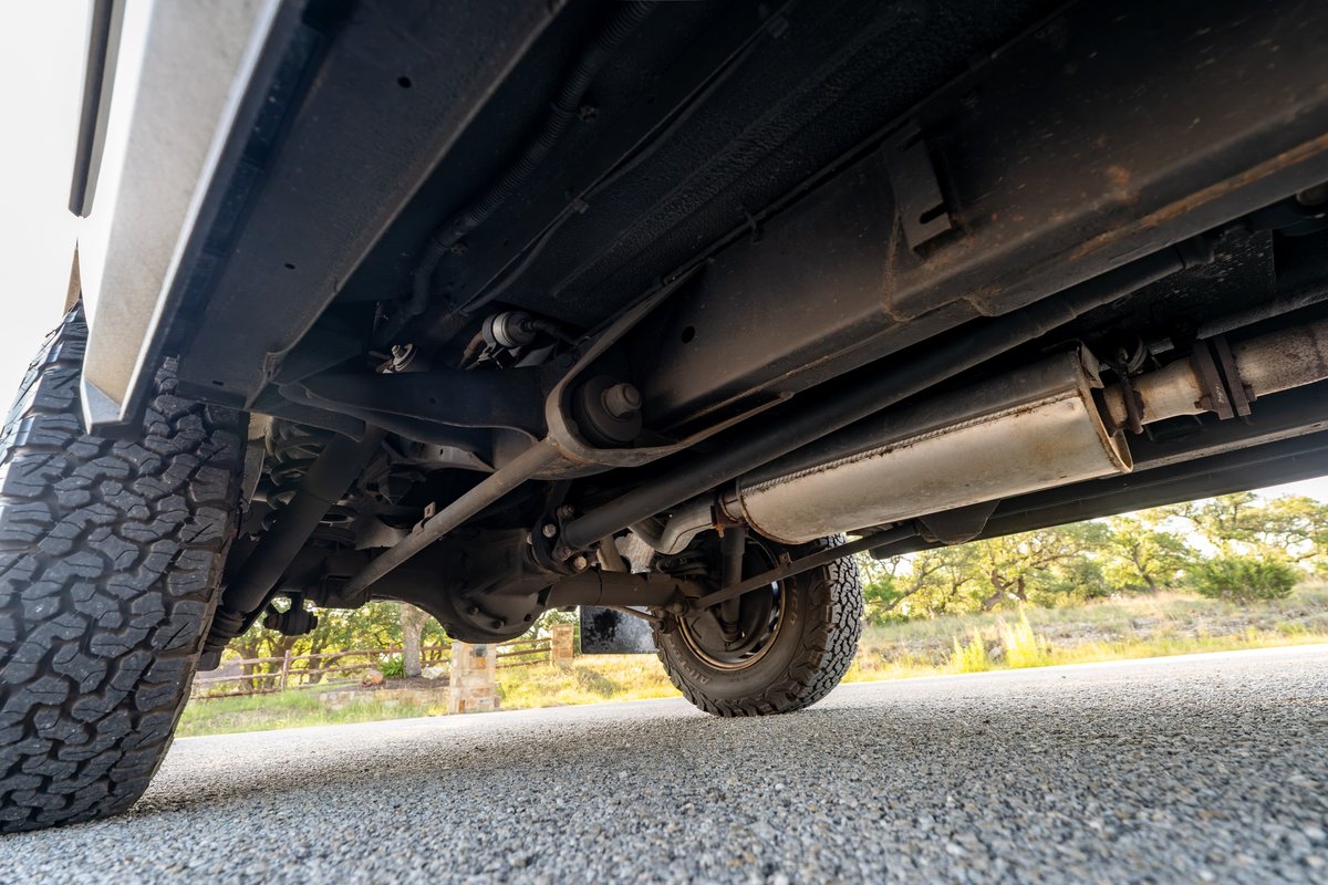 White 1995 Land Rover Range Rover County undercarriage with off-road tires and exhaust.