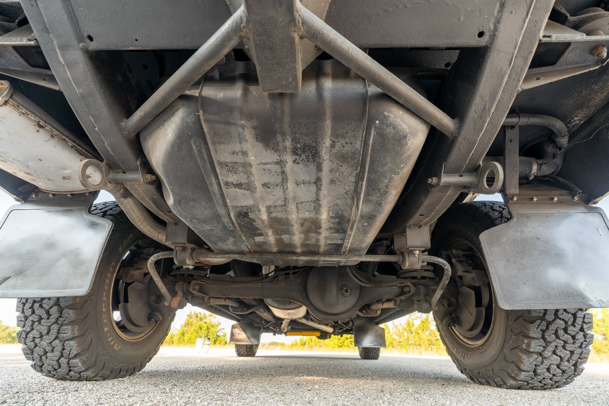 Underside view of a white 1995 Land Rover Range Rover County, showing chassis, fuel tank, and tires.