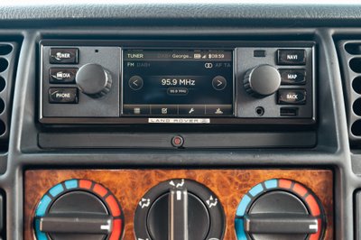 Interior of a white 1995 Land Rover Range Rover County, showing the dashboard infotainment system and climate controls.