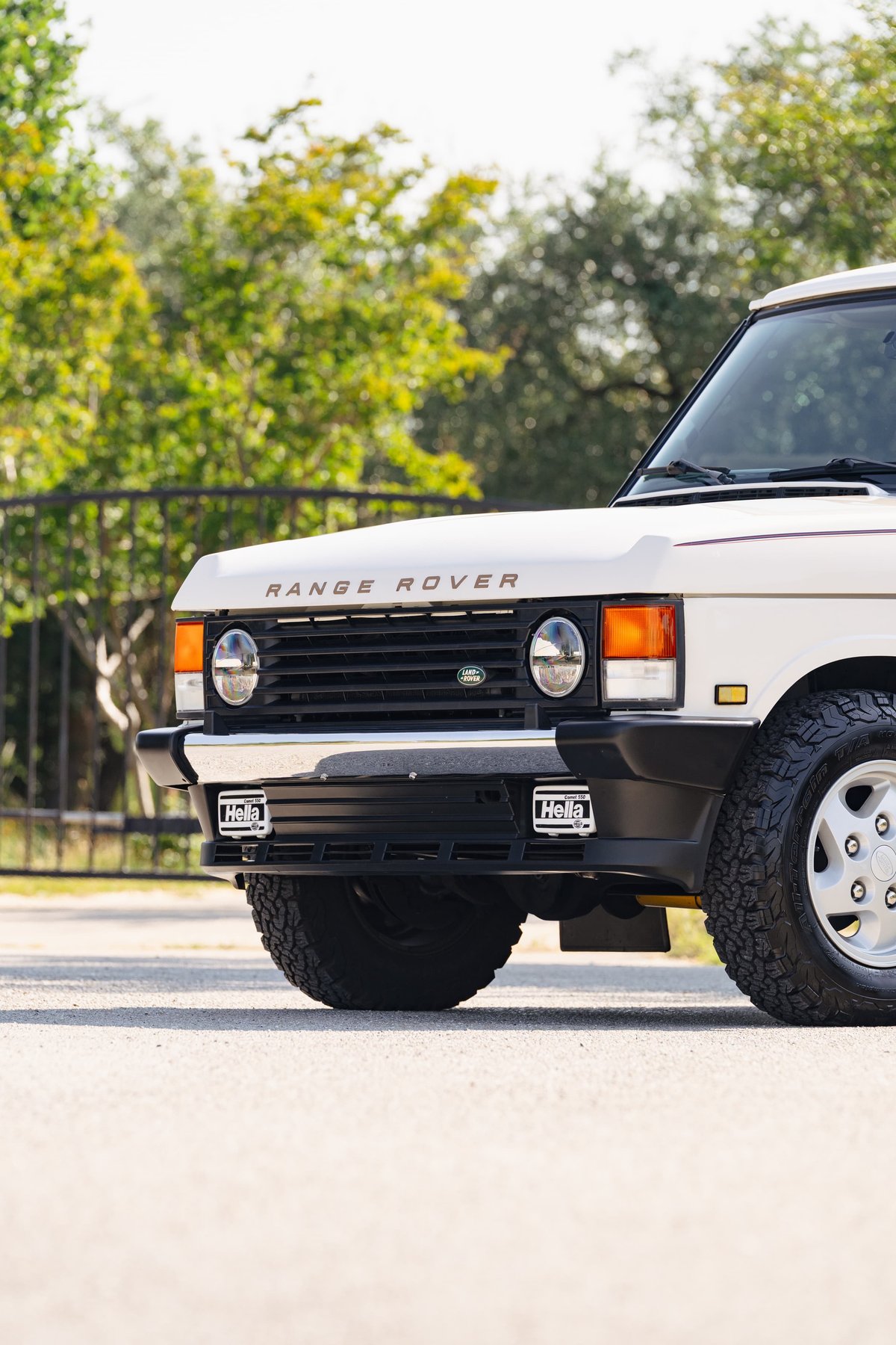 Front view of a white 1995 Range Rover County with Hella fog lights, off-road tires, and silver rims.