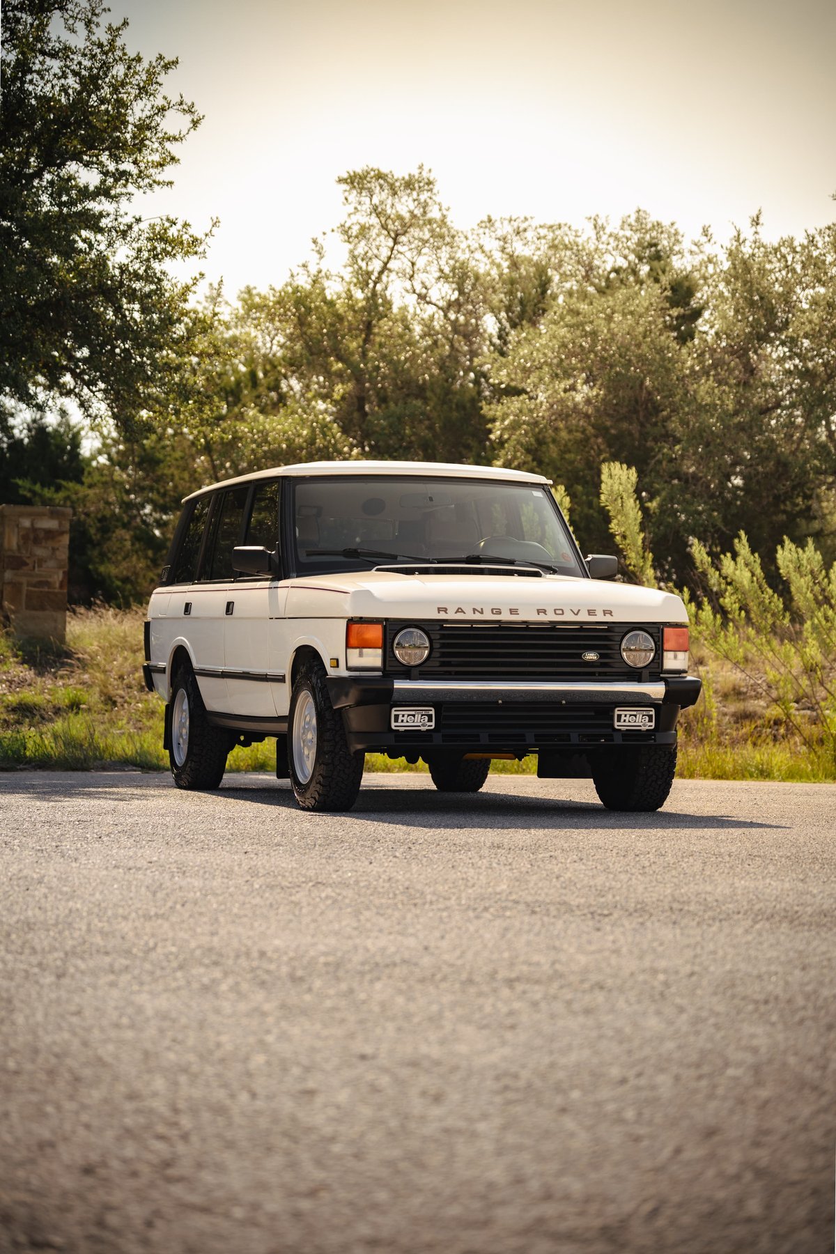 White 1995 Range Rover County Classic with distinct black trim, alloy rims, and Hella fog lights.