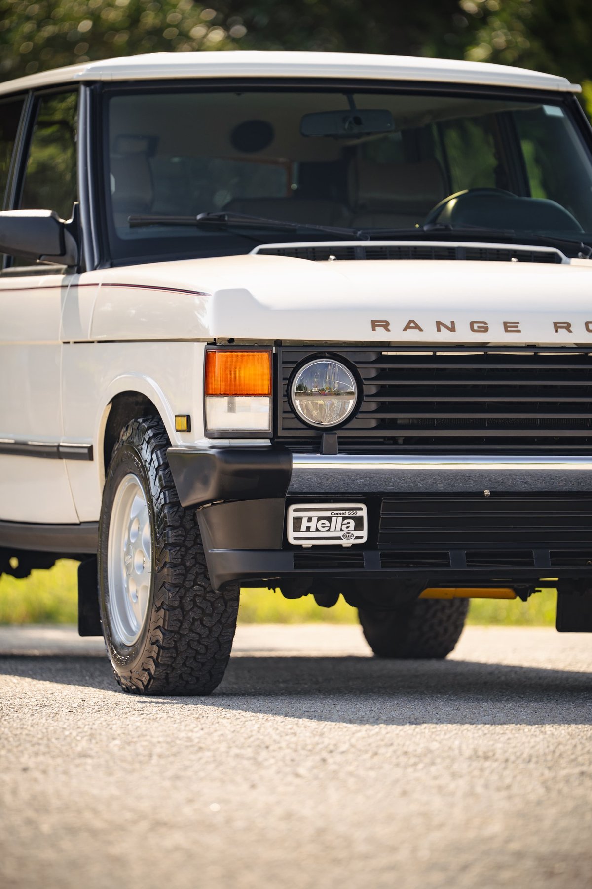 White 1995 Range Rover County front grille with Hella badge and chrome rims.