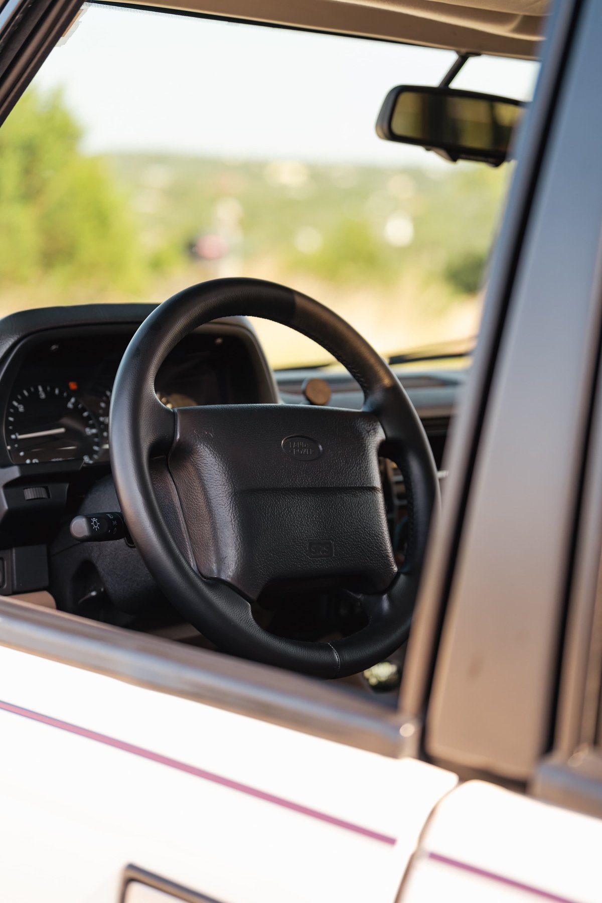 Interior shot of a white 1995 Range Rover County, featuring a black steering wheel and dashboard.