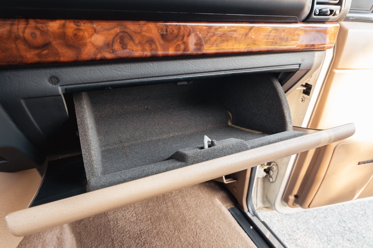 1995 Range Rover County open glove box with wood trim and beige interior.