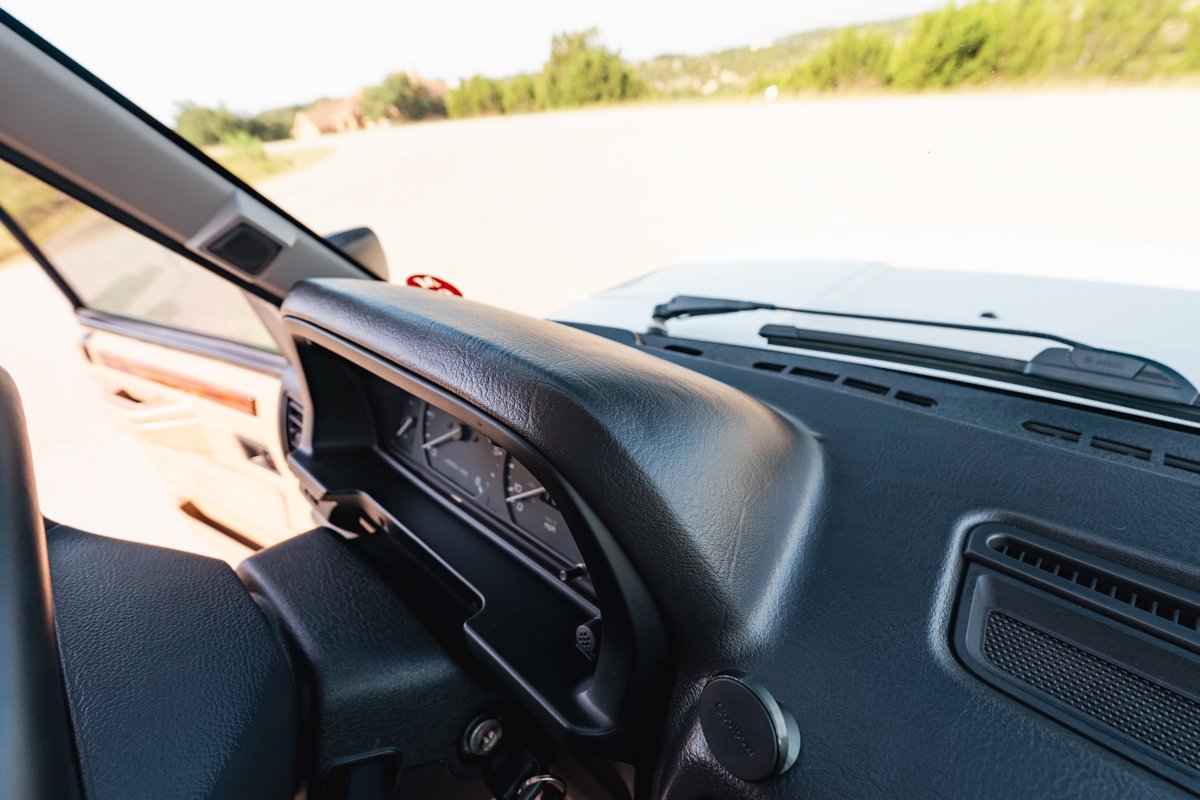 Interior view of a white 1995 Land Rover Range Rover County dashboard with analog gauges and wood trim.