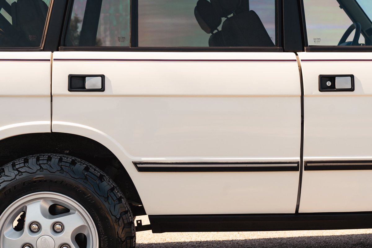 White 1995 Land Rover Range Rover County: detail of door handles, black trim, and alloy rim.