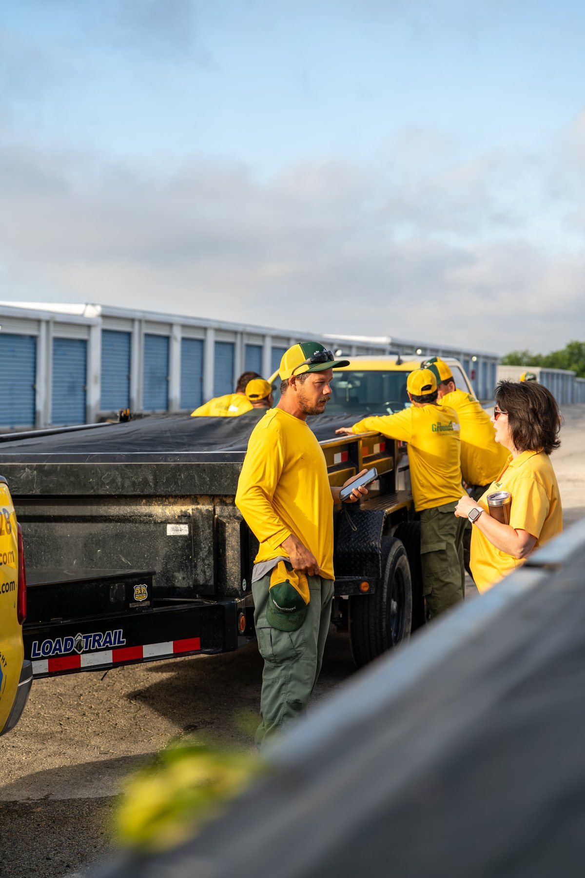 Yellow Load Trail trailer with people in matching yellow livery by yellow truck.