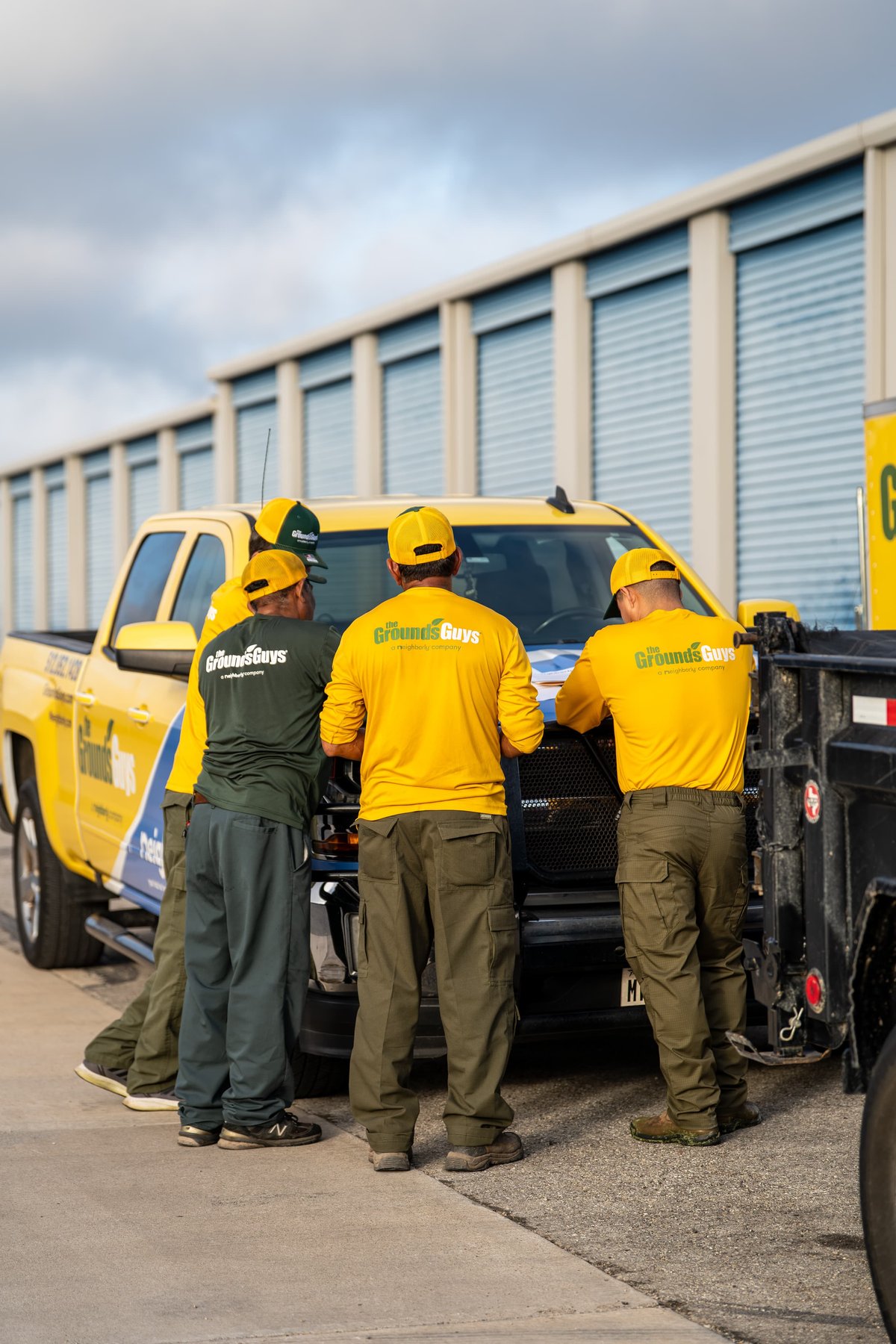 Yellow Chevrolet Silverado pickup truck with "Grounds Guys" livery, front view.