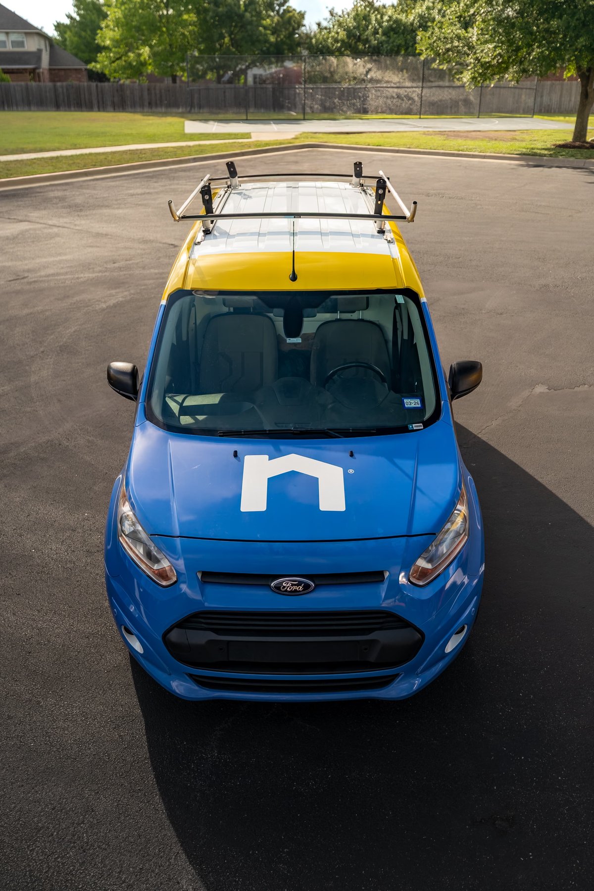 Ford Transit Connect with blue, white, and yellow livery, roof rack.