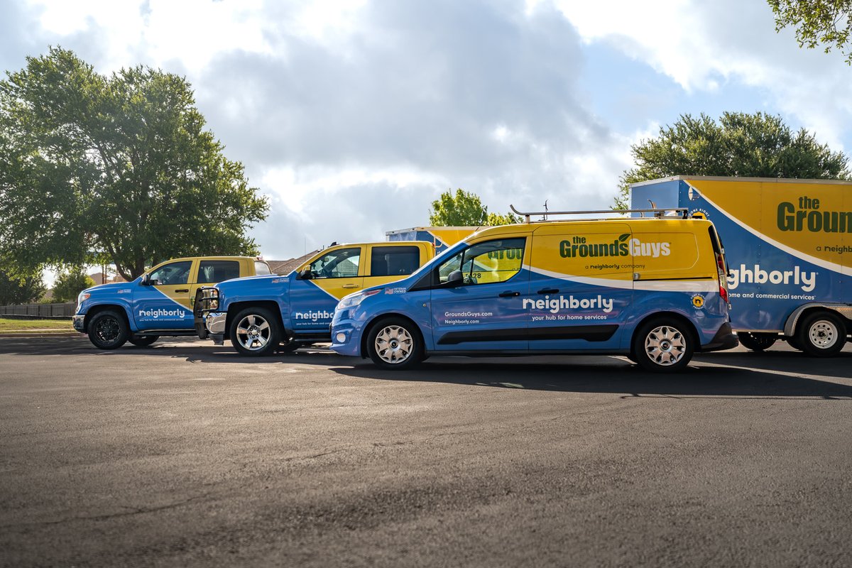 Blue and yellow van with "The Grounds Guys" livery and silver rims.