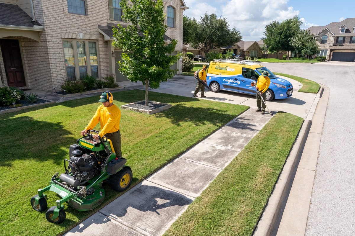A blue Ford Transit with yellow and white livery for "The Grounds Guys."