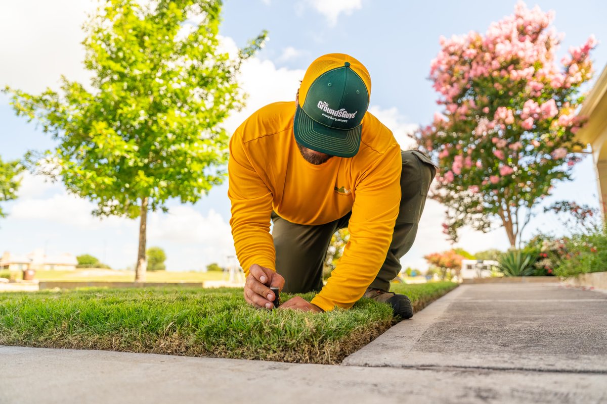 There is no vehicle in this image. The image shows a groundskeeper kneeling and tending to newly laid sod.