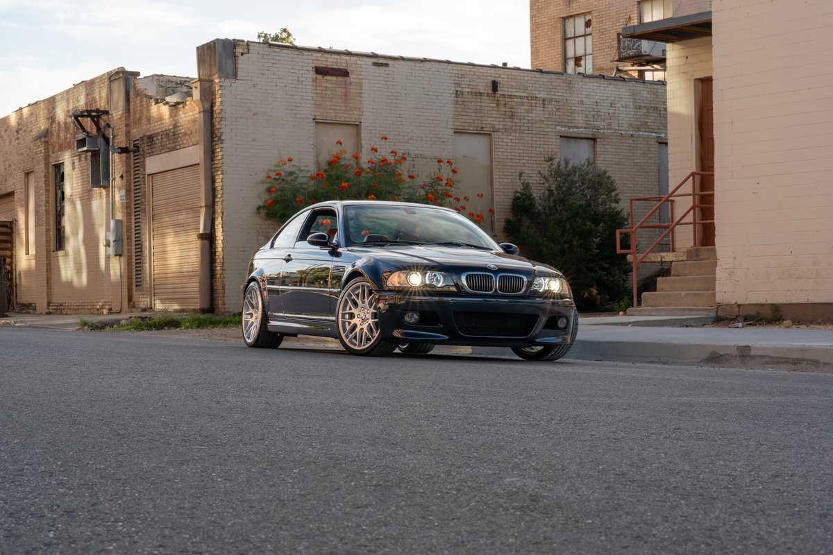 Dark blue 2002 BMW M3 coupe with silver multi-spoke rims parked curbside.