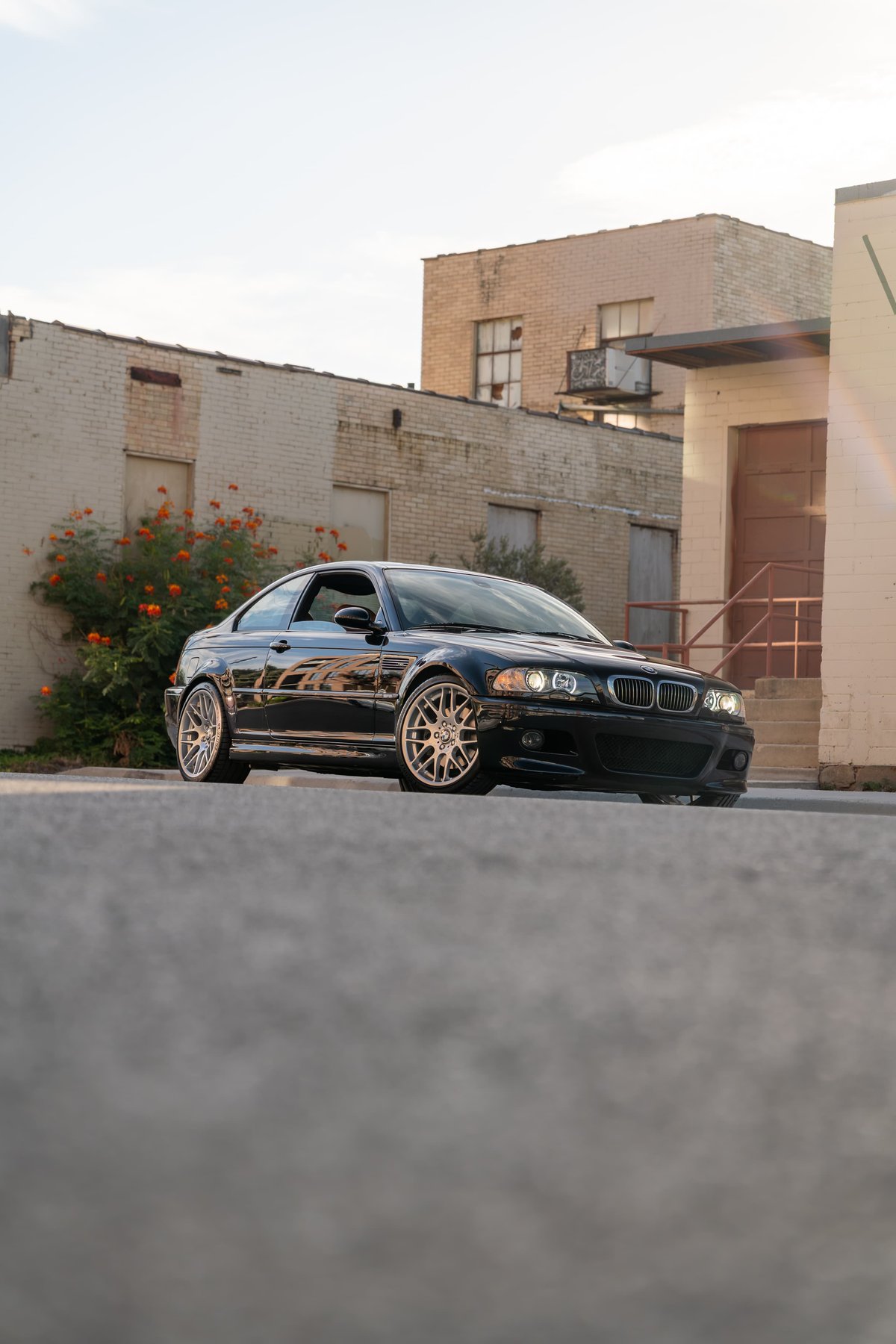 Black 2002 BMW M3 coupe with silver multi-spoke rims parked outdoors.