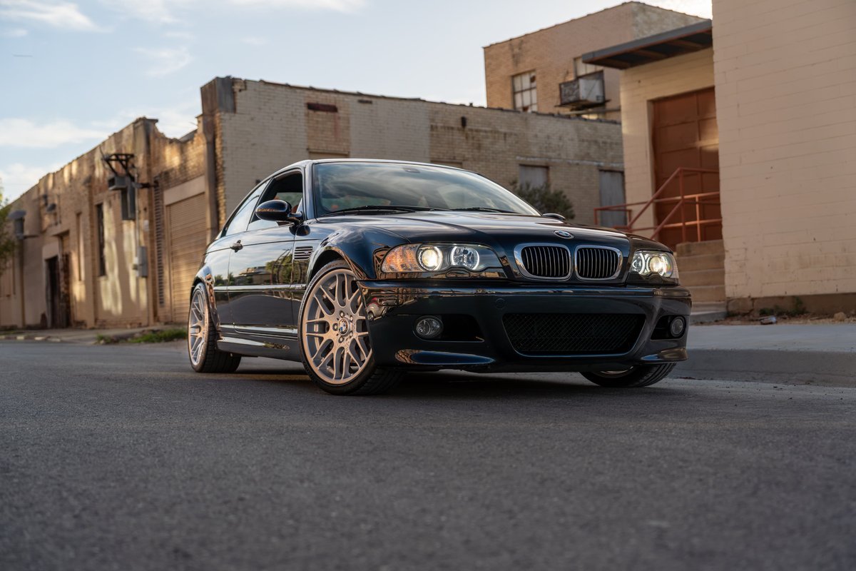 Carbon Black 2002 BMW M3 coupe with silver mesh rims parked on asphalt.