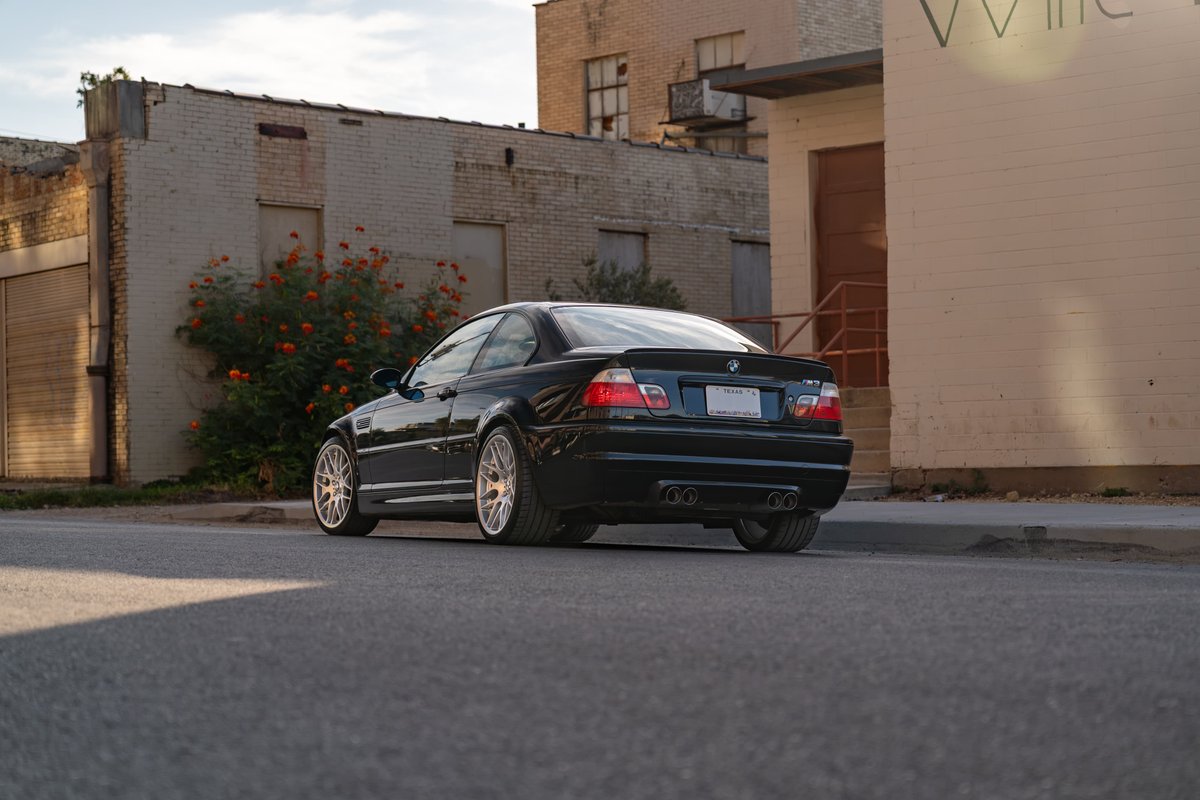 Black 2002 BMW M3 with multi-spoke rims, parked on asphalt.