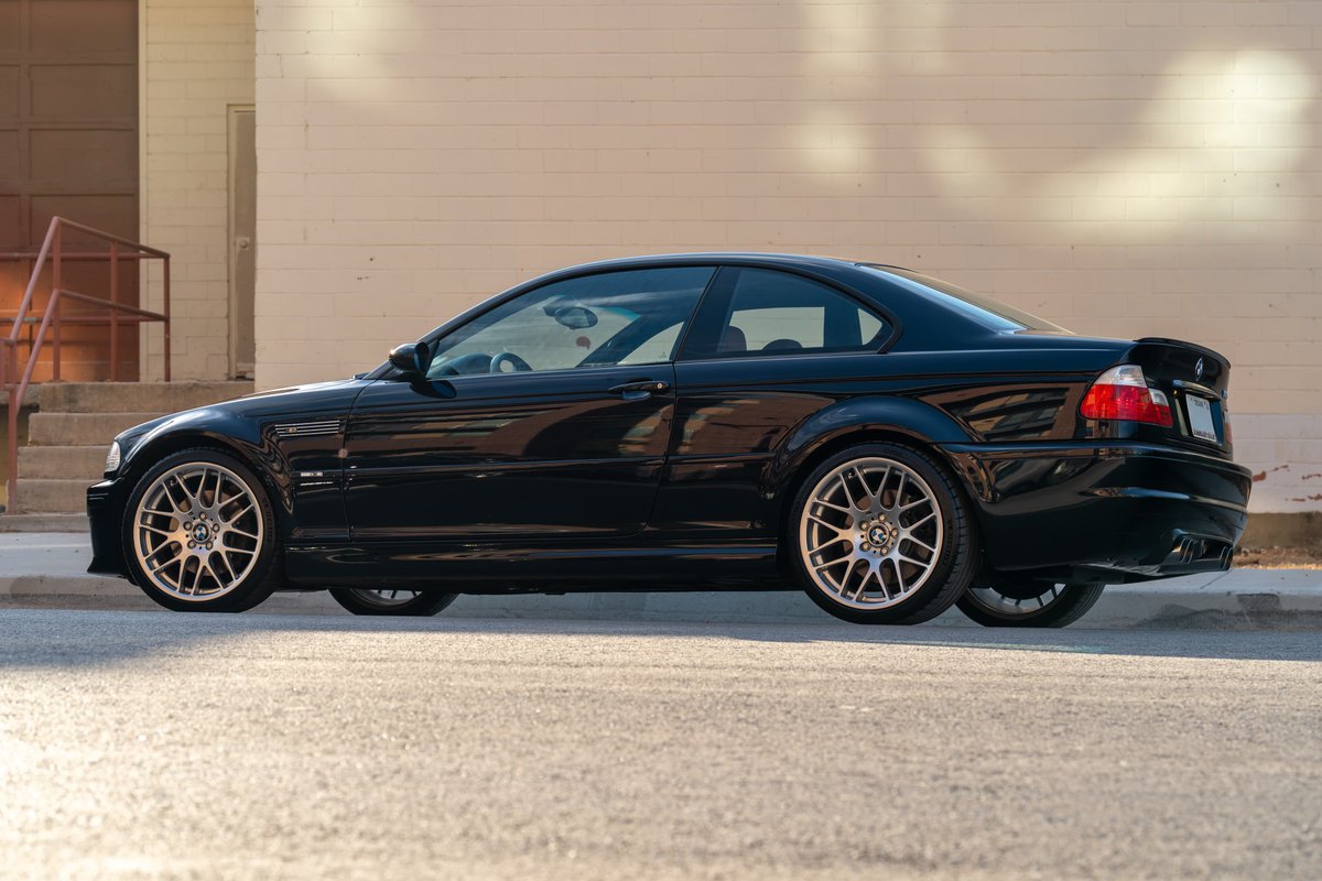 Side profile of a black 2002 BMW M3 coupe with silver multi-spoke rims.