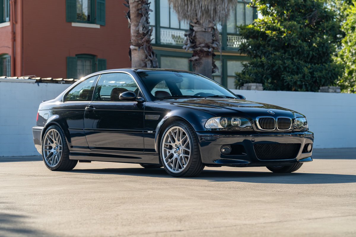 A black 2002 BMW M3 coupe with silver multi-spoke rims and M badging.