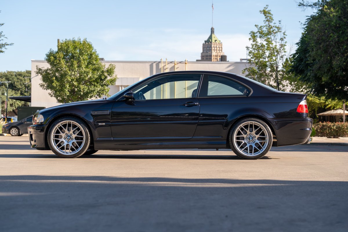 Black 2002 BMW M3 coupe with silver multi-spoke rims parked outside.