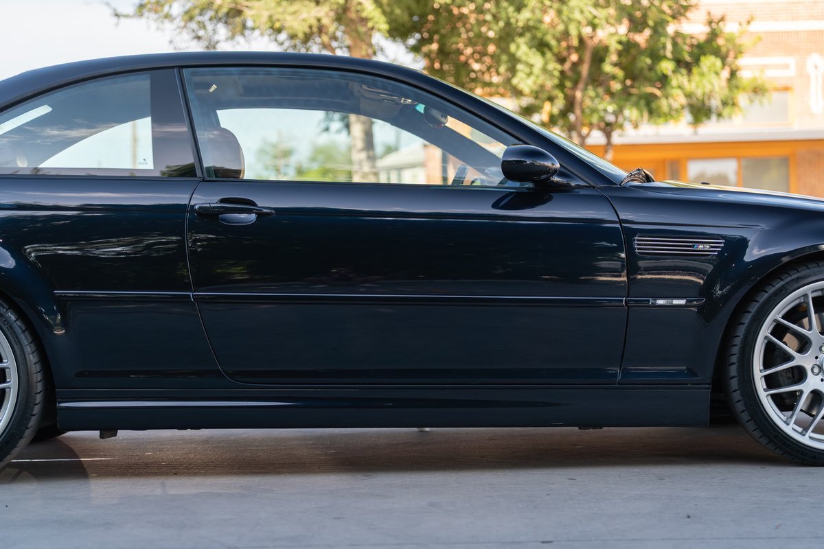 Carbon Black 2002 BMW M3 coupe profile, showcasing M3 fender vent and multi-spoke rims.