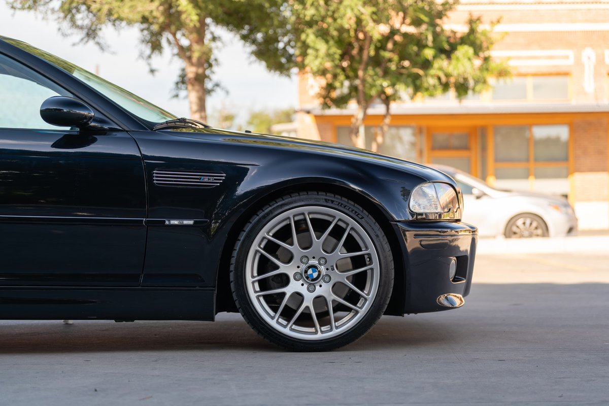 Black 2002 BMW M3 E46 shows off its silver multi-spoke rims and fender vent.