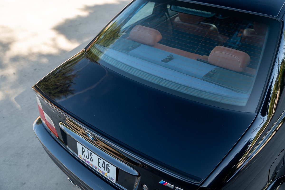 Black 2002 BMW M3 E46 trunk with chrome trim and red interior headrests.