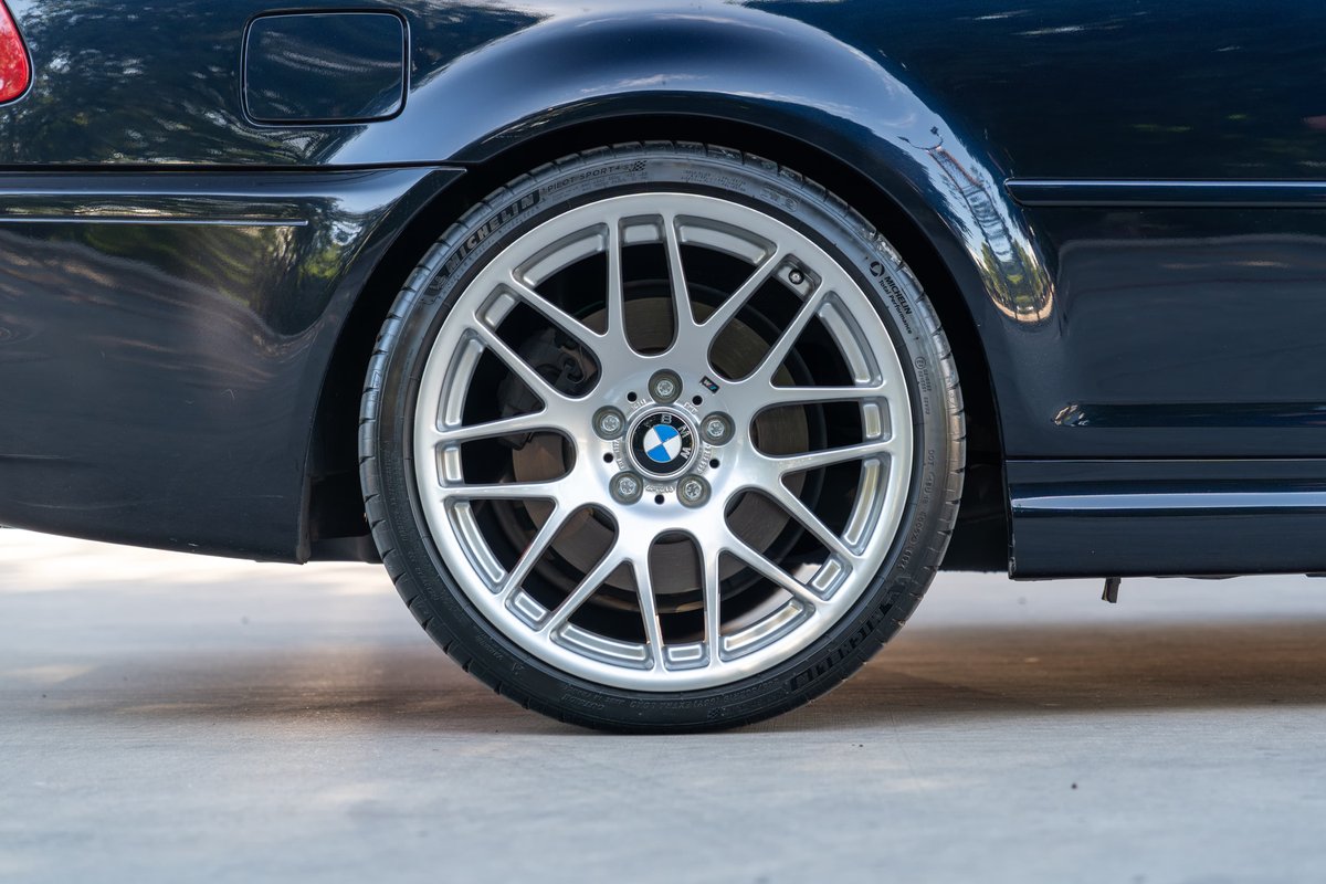 Detail of a dark blue 2002 BMW M3 rear wheel and tire.