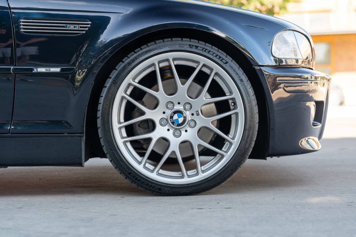 Carbon black 2002 BMW M3 front wheel with silver alloy rims and M badging.
