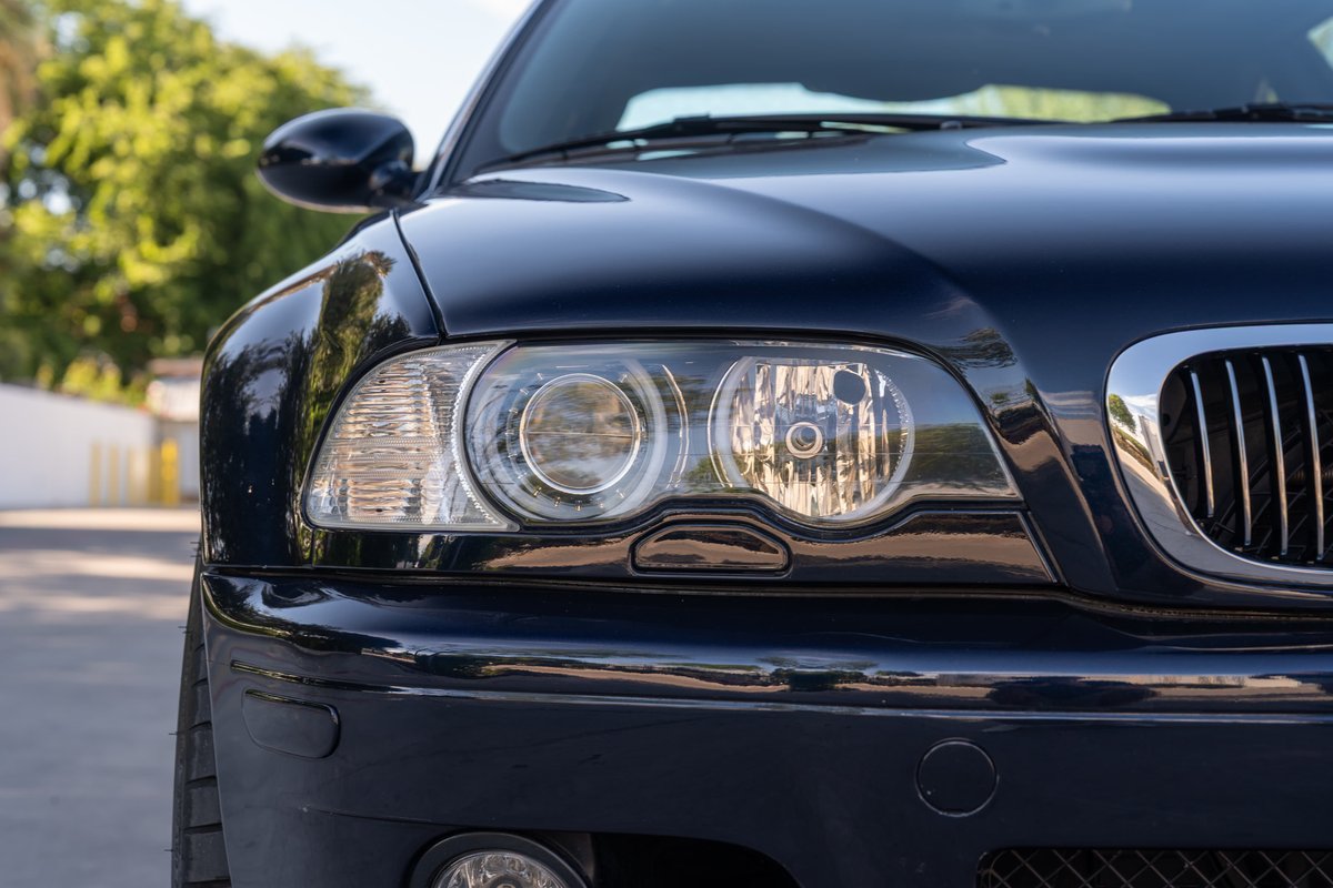 Carbon black 2002 BMW M3 headlight detail with chrome grille trim.