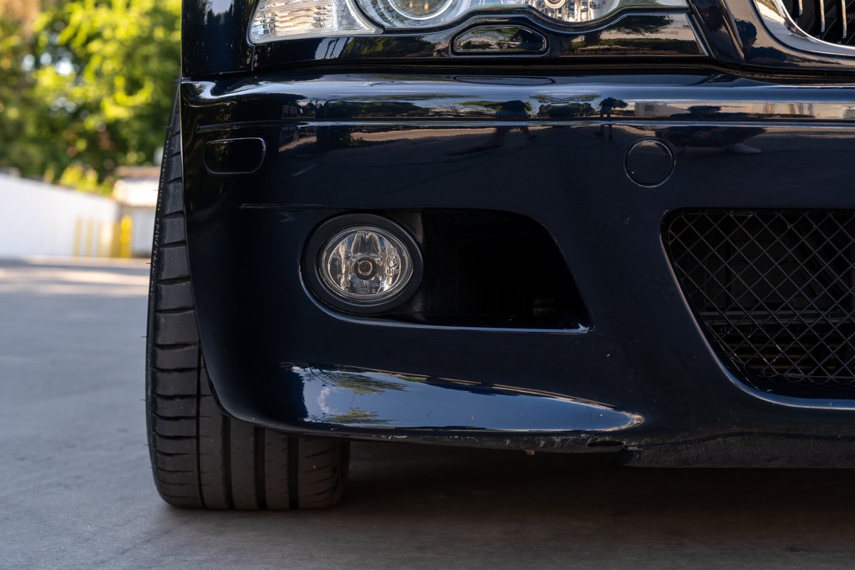 Close-up of a dark blue 2002 BMW M3 front bumper and tire.