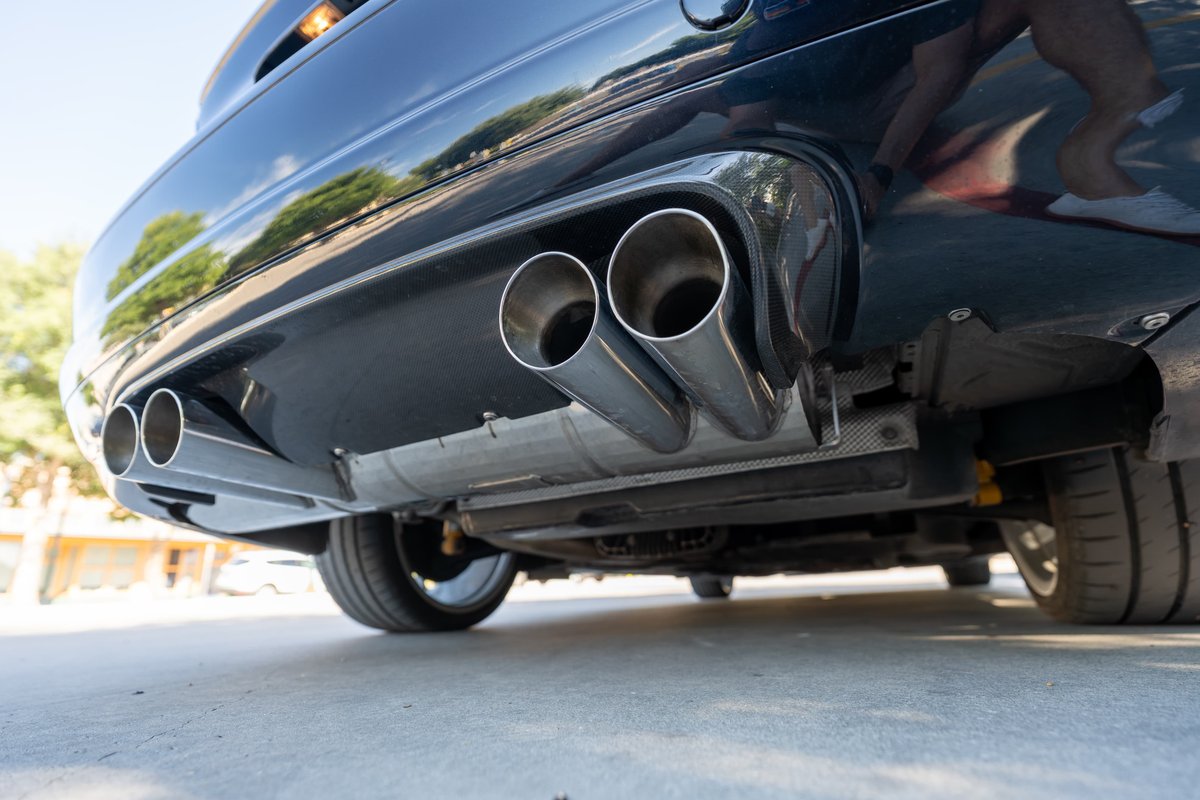 Close-up of a black 2002 BMW M3's quad exhaust tips and diffuser.