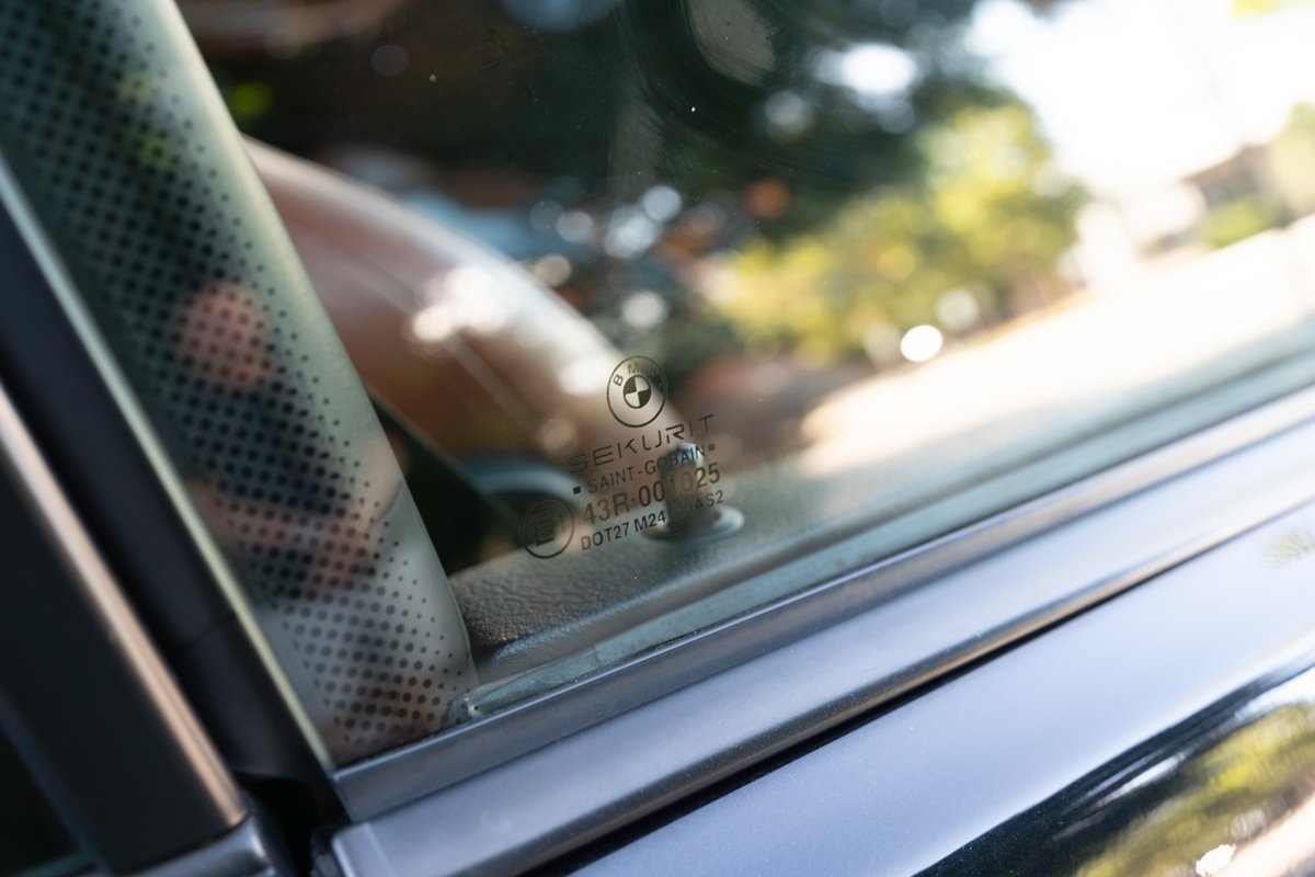 Close-up of 2002 BMW M3 side window with Saint-Gobain Sekurit glass, carbon black trim.