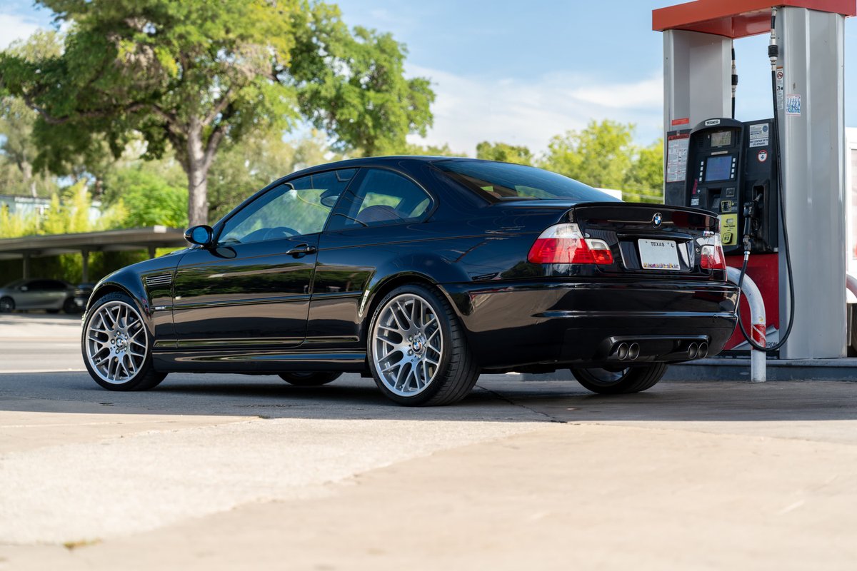 Black 2002 BMW M3 coupe with aftermarket silver mesh rims and quad exhaust tips.
