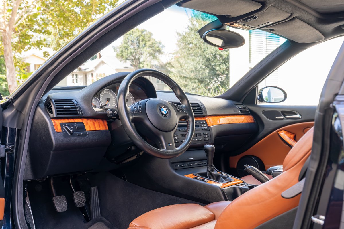 Interior view of a black 2002 BMW M3 convertible with tan leather seats & wood trim.