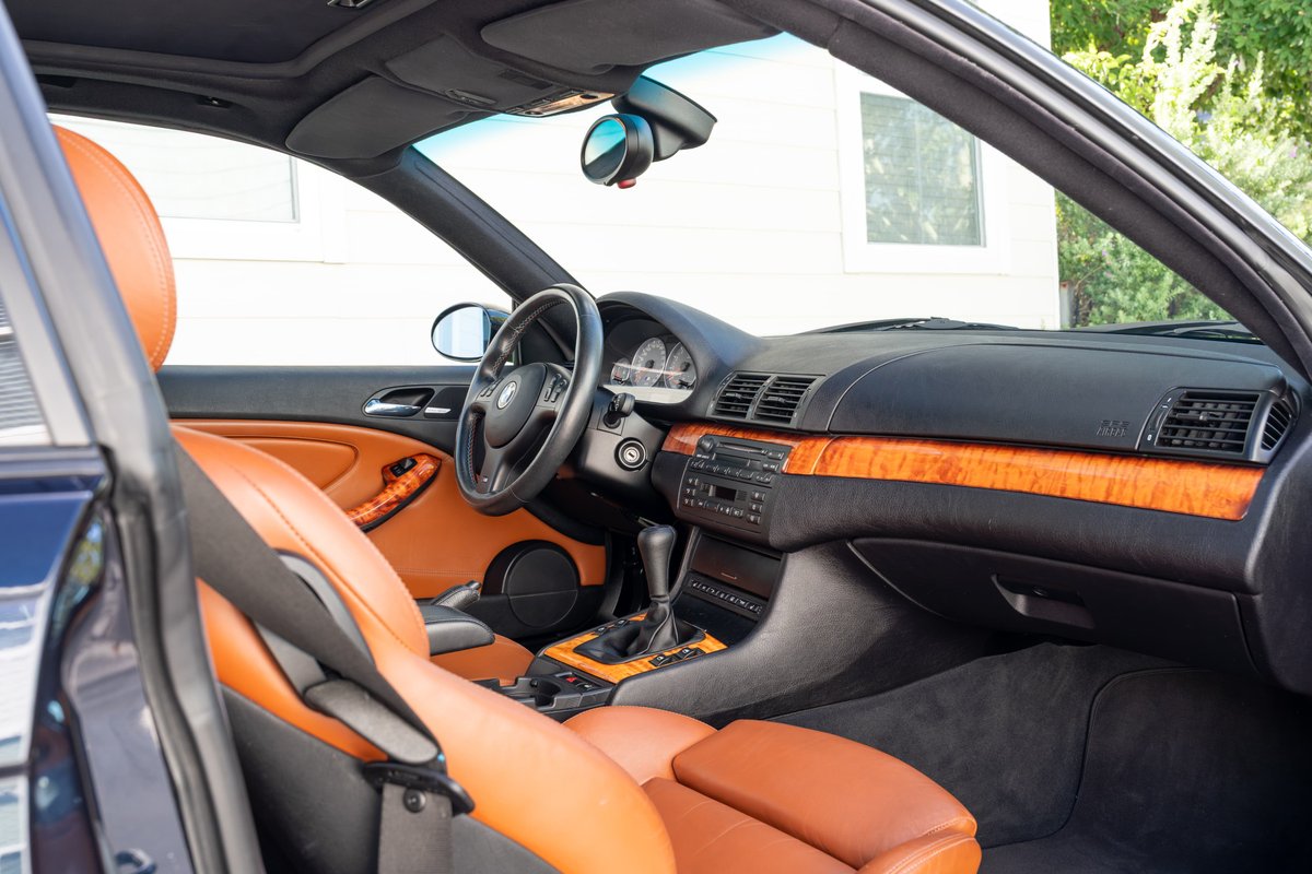 Carbon black 2002 BMW M3 interior with tan leather seats and wood trim.