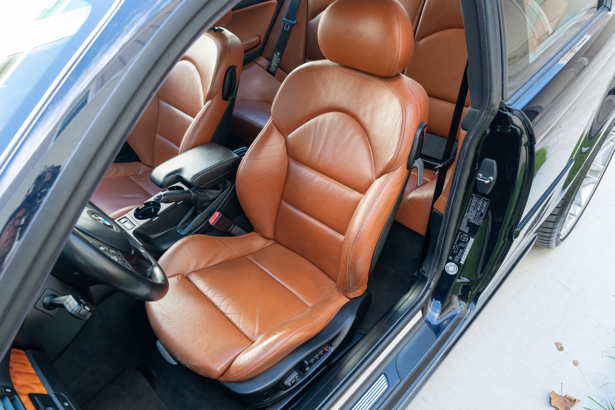 Black 2002 BMW M3 interior with tan leather sport seats, steering wheel and center console.