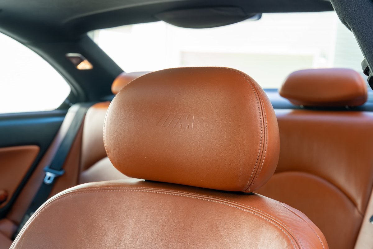 Brown leather M3 interior with embossed M logo on headrest. 2002 BMW M3 cabin detail.
