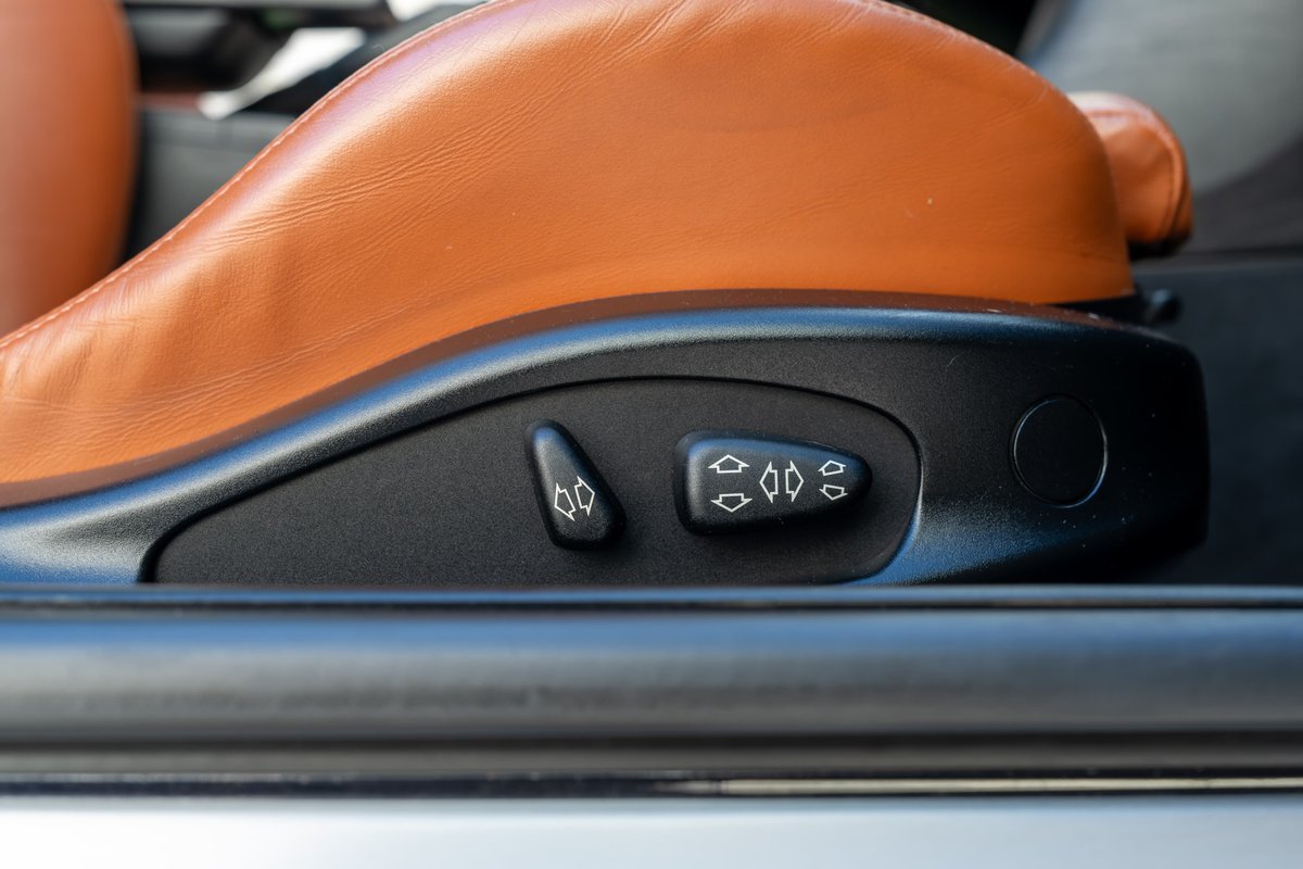Close-up of power seat adjustment controls on a 2002 BMW M3 convertible with tan leather interior.