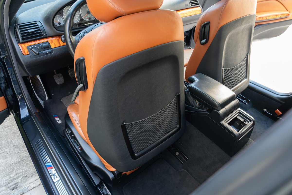 Interior shot of a black 2002 BMW M3 with tan leather seats and wood trim.