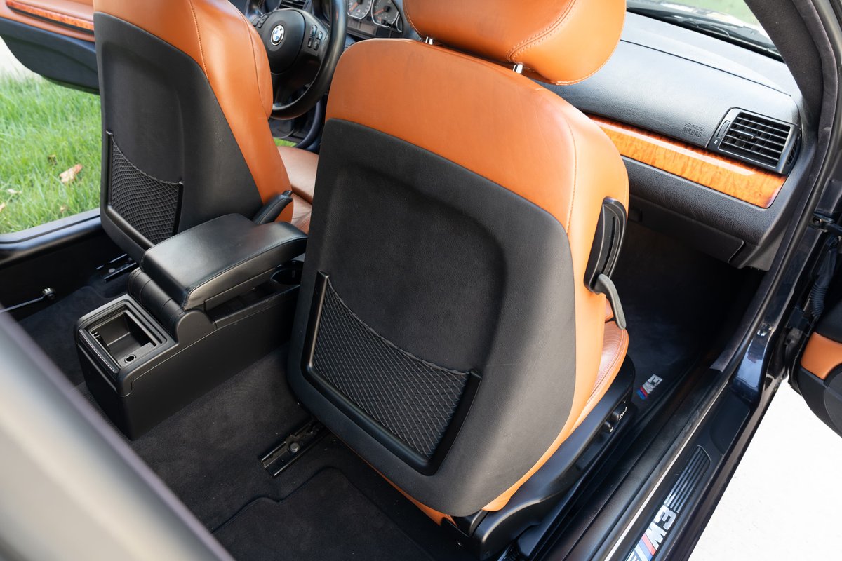 2002 BMW M3 interior with black and tan leather seats, wood trim, and M3 door sills.