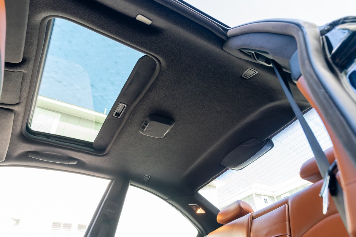 Interior shot of a 2002 BMW M3 with a sunroof open and tan leather seats.