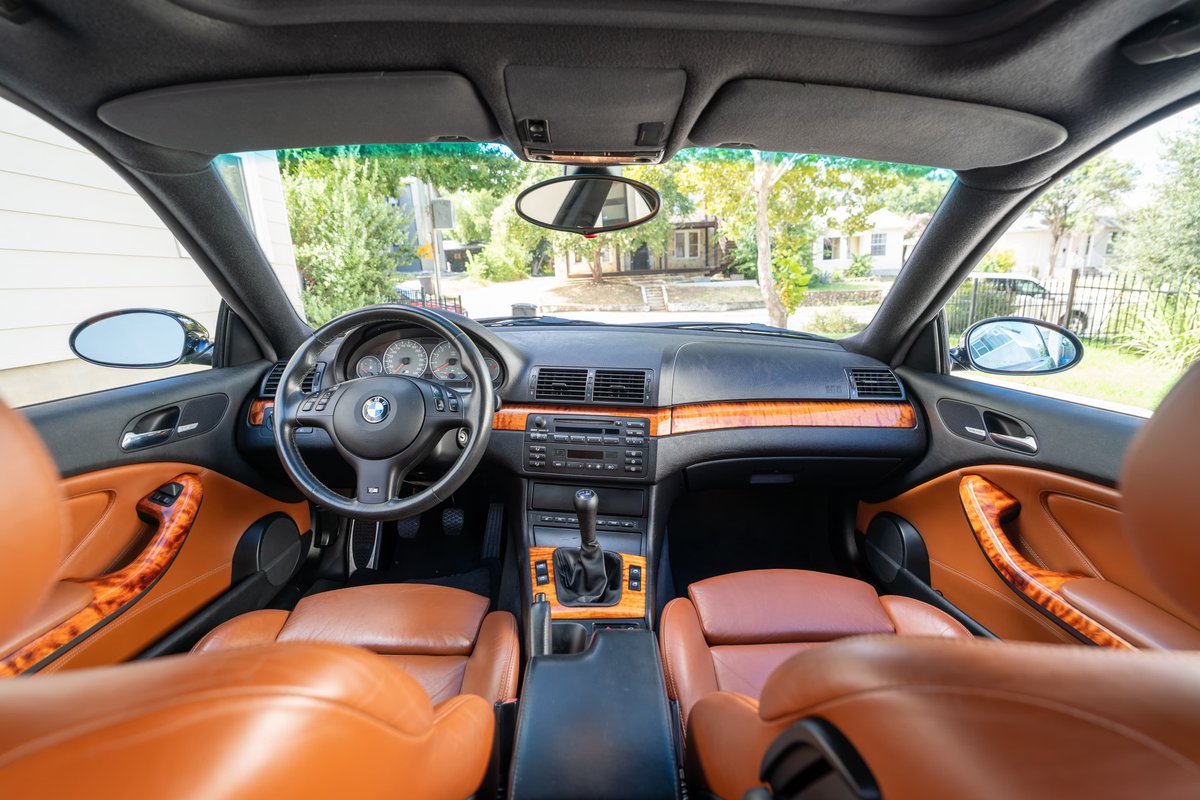 Interior of a black 2002 BMW M3 with tan leather seats and wood trim.